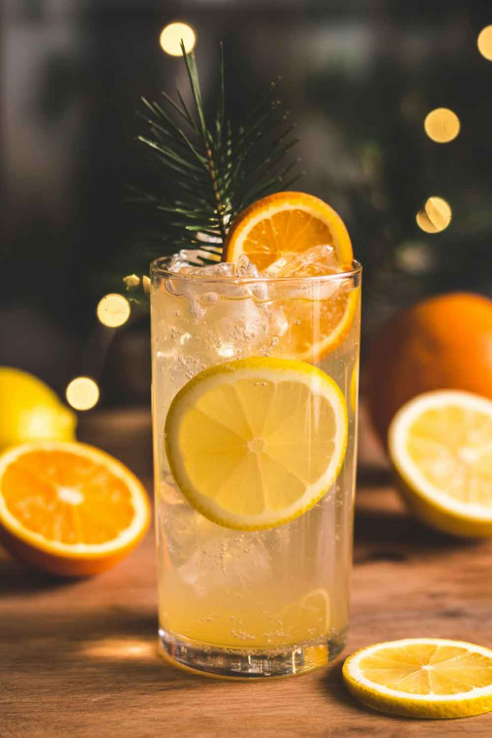 Bright citrus and ginger mocktail in a tall glass with lemon and orange slices, set in a cozy holiday home setting.