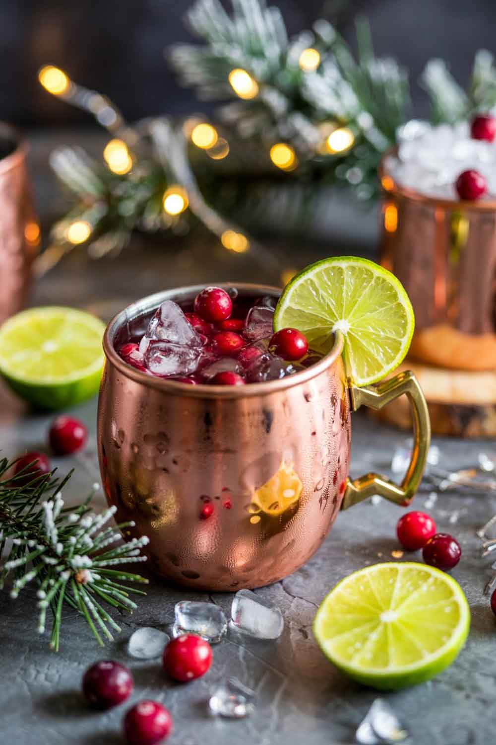 Cranberry Moscow Mule Cranberry Moscow Mule in a copper mug with cranberries and lime, on a wooden table with frosted berries and evergreen accents.